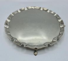 A sterling silver circular card tray with cast border on three feet. 21cm(d) by Edward Barnard &