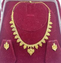 A South Asian unmarked yellow metal necklace with matching earrings marked 88. 21.6g.