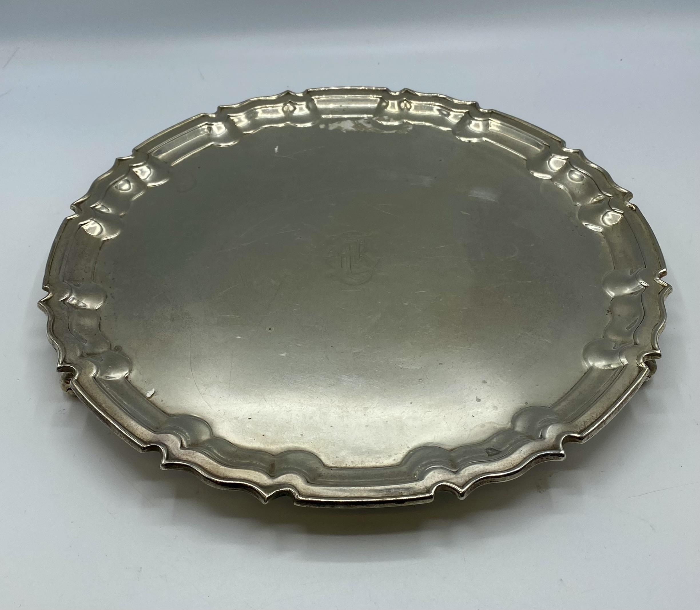 A sterling silver circular tray on three scroll feet by William Hutton and Sons Ltd, Sheffield 1922.