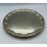 A sterling silver circular tray on three scroll feet by William Hutton and Sons Ltd, Sheffield 1922.