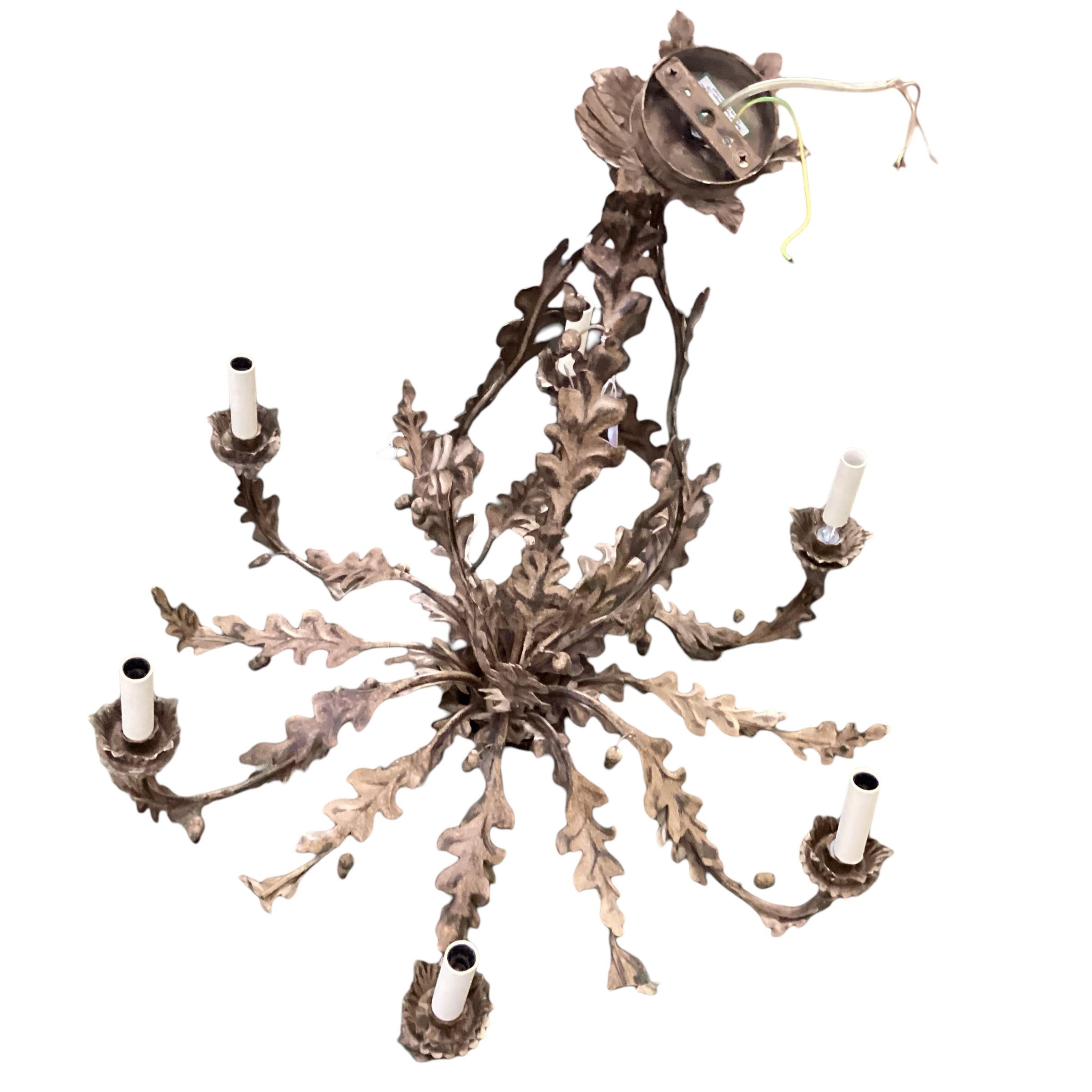 A contemporary decorative light metal six branch chandelier, with ornate leaf decoration and finial,