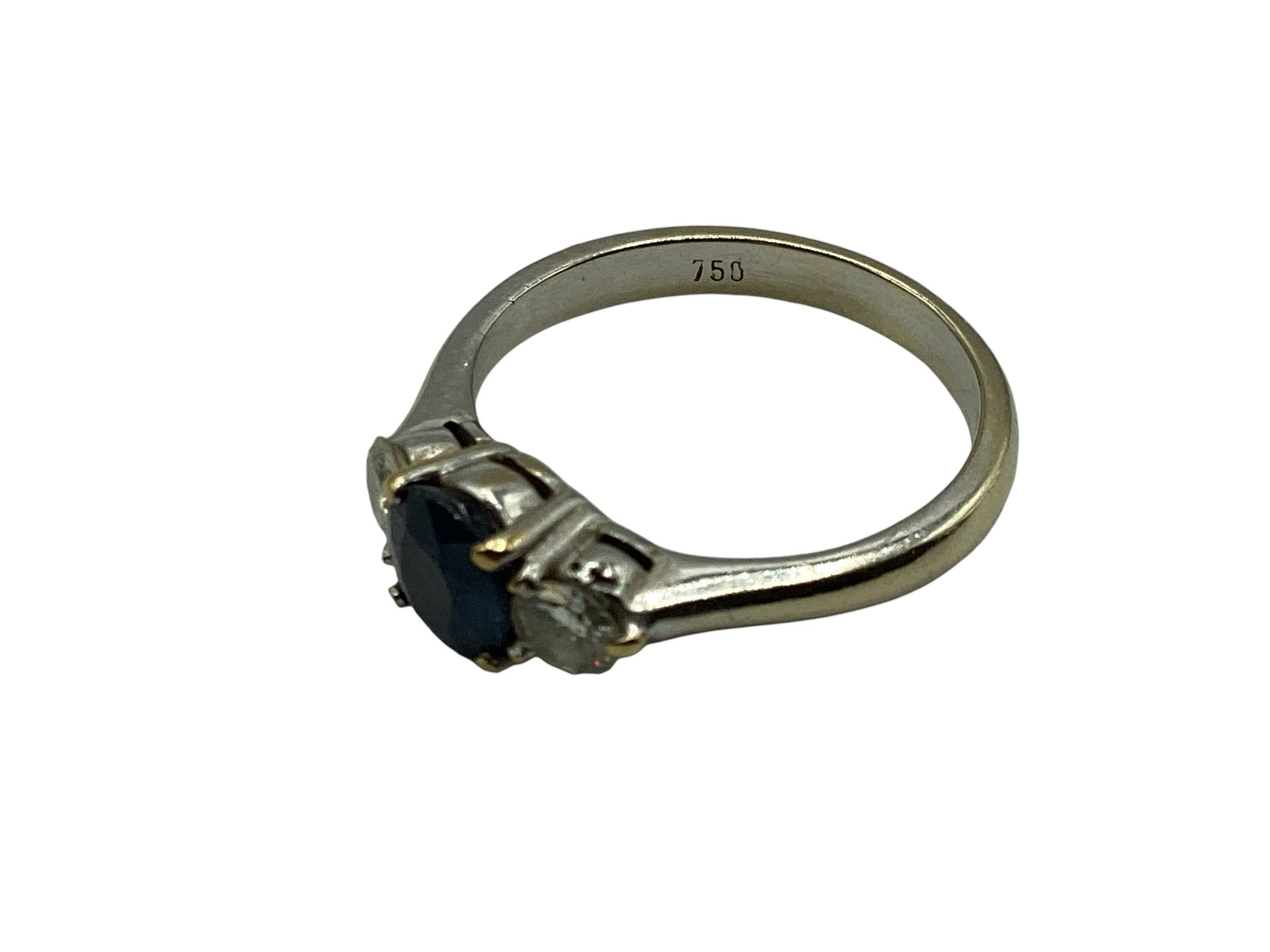 An 18ct white gold sapphire and diamond ring central oval free cut sapphire with brilliant cut