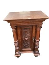 A heavy carved single door side cabinet, with columns to each side, some old splits and general wear