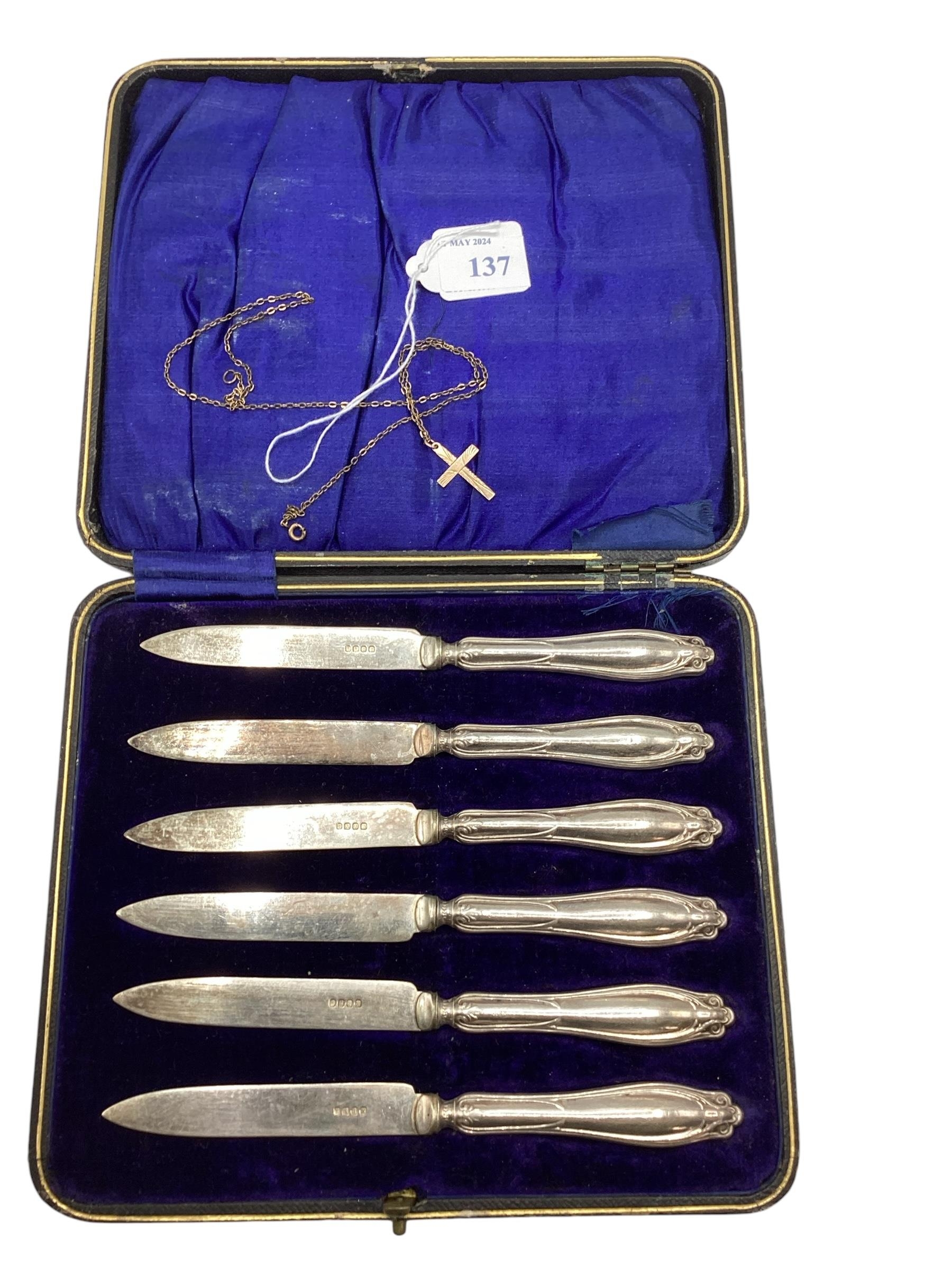 A 9ct gold cross on a yellow metal chain, and a cased set of EPNS butter knives,