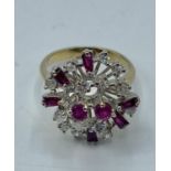 An unmarked yellow and white metal ruby and diamond cluster ring. 5.75g. Size L.
