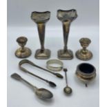 A collection of sterling silver items to include a pair of trumpet vases, candle sticks, napkin ring