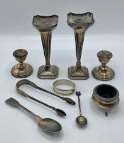 A collection of sterling silver items to include a pair of trumpet vases, candle sticks, napkin ring