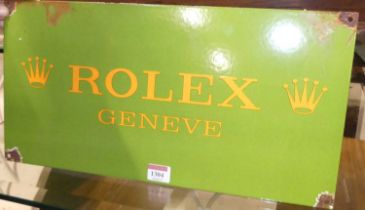 An enamel on metal wall mounted sign bearing text 'Rolex Geneve', 23 x 46cm