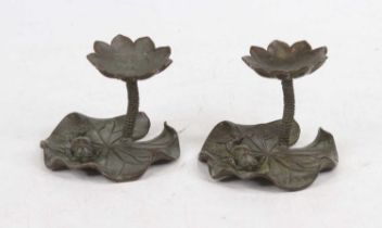A pair of modern bronzed metal table candlesticks, each sconce in the form of a flower, raised on