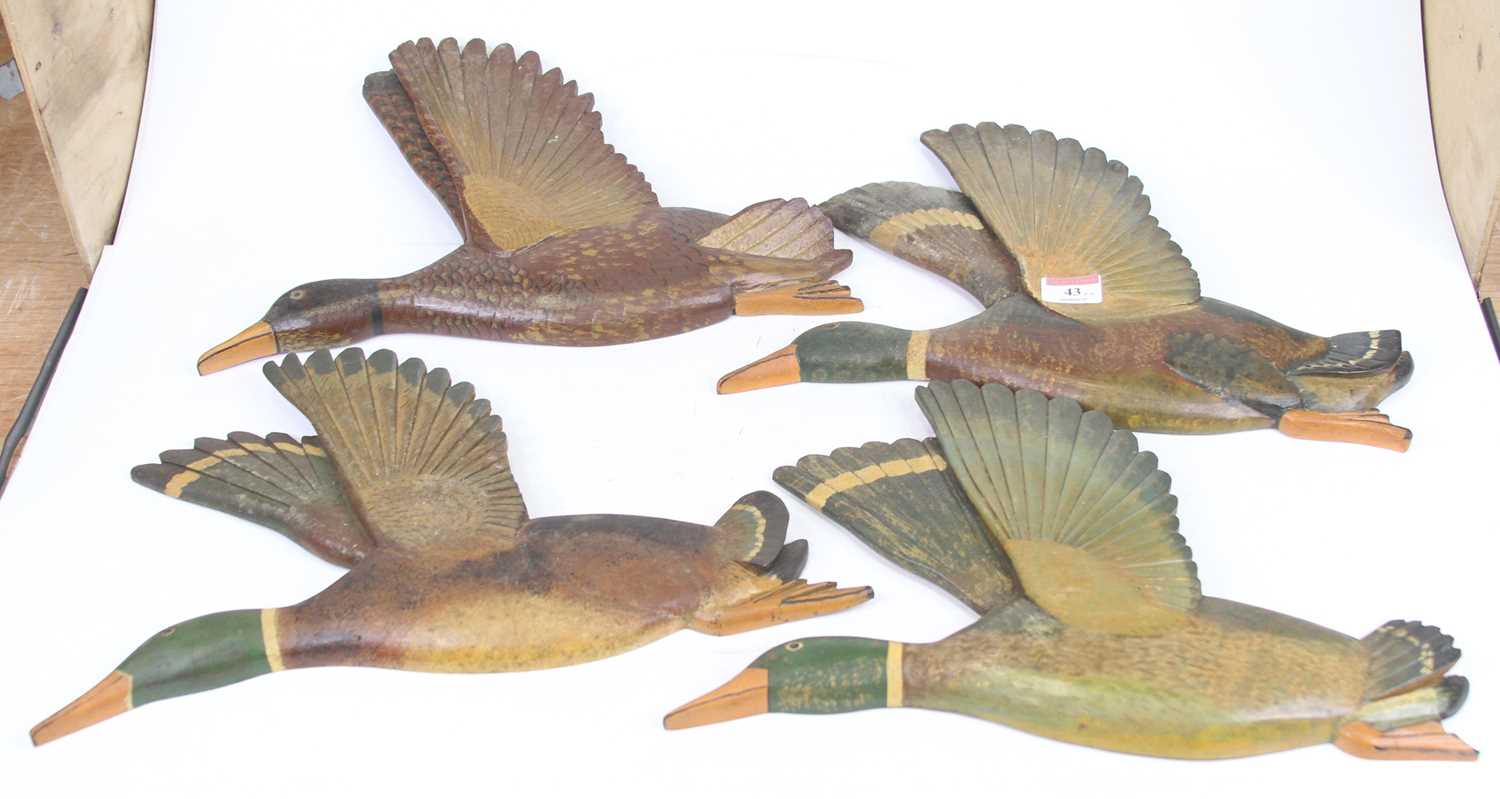 A set of four carved and painted pine wall plaques, each in the form of a flying duck One has been