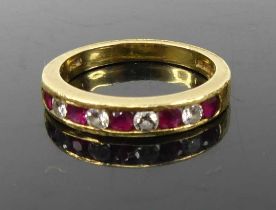A contemporary 18ct gold ruby and diamond set half eternity ring, channel set with 9 alternating