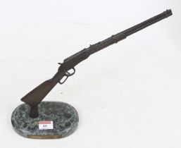 A bronzed metal model of a Winchester model 94 lever action rifle, mounted to polished hardstone