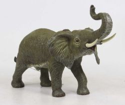 A cold painted bronzed metal model of an elephant, shown standing with trunk raised, height 22cm