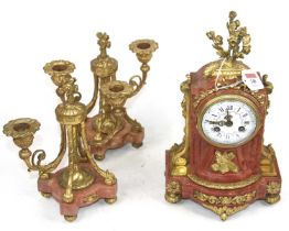 A 19th century French red polished hardstone and gilt metal clock garniture, the enamelled dial