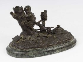 A circa 1900 bronze inkstand, of oval form, featuring a boy escaping a playful dog, the whole raised