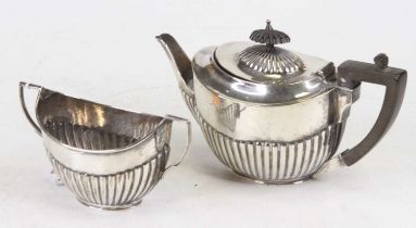 A George V silver bachelor's teapot of reeded oval shape together with a matching sugar bowl, London