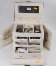 A cream simulated leather clad jewellery box, the hinged lid opening to reveal various drawers