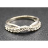 A modern white metal and diamond set half hoop ring, arranged as 13 small graduated brilliants, to a