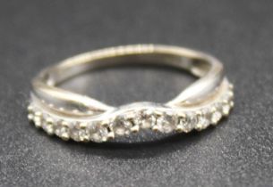 A modern white metal and diamond set half hoop ring, arranged as 13 small graduated brilliants, to a