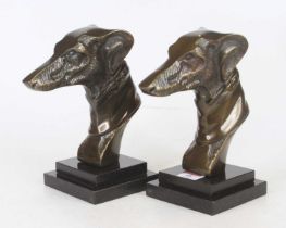A pair of bronzed metal models of greyhound heads, each upon a black polished hardstone plinth, h.
