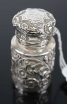 A George V silver and embossed cylindrical scent bottle, with hinged cover and glass liner, 7cm