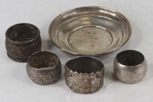 Four various silver napkin rings together with a plain silver circular dish, various dates and