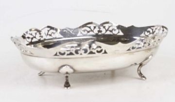 A George V silver dish having a shaped pierced rim standing on scrolled pad feet, Birmingham 1913,