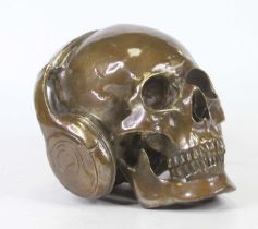 A bronzed model of a skull wearing headphones, h.15cm