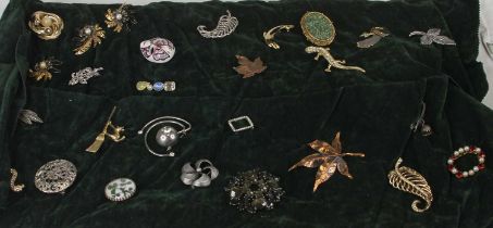 A jeweller's suede roll containing a large quantity of costume jewellery, largely being brooches,