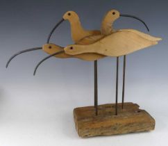 A carved pine and iron sculpture group of four curlew, mounted on a naturalistic pine base, h.51cm