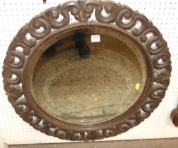 An early 20th century oak floral carved, pierced, beaded and bevelled circular wall mirror, dia.