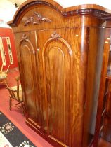 A mid-Victorian mahogany round cornered double door wardrobe, having floral crested arched doors,