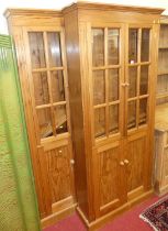 A pair of contemporary pine bookcases, each having twin glazed upper doors over twin panelled