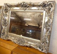 A contemporary silvered and heavy floral decorated rectangular bevelled wall mirror, 82 x 106cm