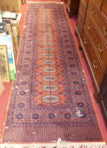 A Persian style machine woven woollen red ground Bokhara hall runner (with losses to surface), 350 x
