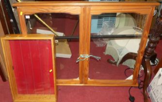 A pine wall mounted double door glazed collectors display cabinet, with interior glass shelves;