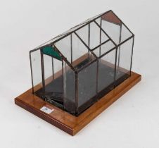 A Victorian style glazed terrarium of architectural form standing on a rectangular walnut plinth,