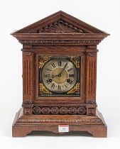 An early 20th century oak cased mantel clock of architectural form, the silvered chapter ring with