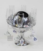 A polished metal ice bucket in the form of Saturn, together with six glass champagne flutes,