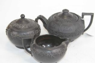 A Wedgwood black basalt three-piece tea set, comprising teapot, h.11cm, sugar bowl and cream jug