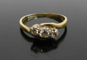 An 18ct gold diamond three stone ring, the three round cuts in a crossover setting, total diamond