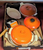 A collection of Le Creuset orange enamelled cast iron cookware, together with two others similar