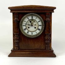 An early 20th century oak cased mantel clock, the enamel chapter ring showing Roman numerals, having