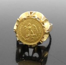 A modern yellow metal signet ring set with a small Mexican gold coin, ring and setting are