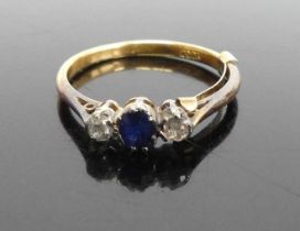 An 18 carat gold sapphire and diamond three stone ring, arranged as an oval cut sapphire flanked