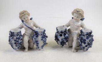 *A pair of Sitzendorf porcelain figural spill vases, each in the form of a cherub clutching floral