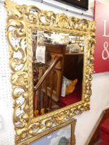 *An Italian floral scroll gilt wood framed square bevelled wall mirror, having scallop shell detail,