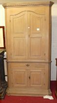 A 19th century limed oak freestanding corner cupboard, having twin arched and recessed panelled