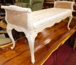 A French cream painted and floral decorated long window seat, having double split cane ends,