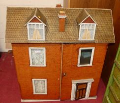 A vintage three-storey doll's house, having a hinged upper compartment, the twin hinged front